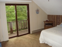 Bedroom on upper level features sliding glass doors to deck with view of golf course. 